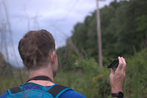 A man listening to bird calls in a field.