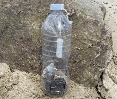 Photo of a clear, disposable water bottle with a cotton tampon hanging inside.