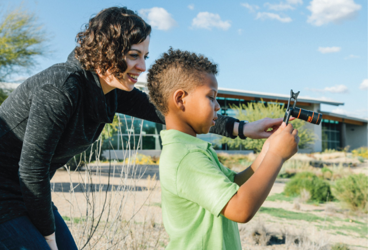 teacher helping student take a picture of biodiversity