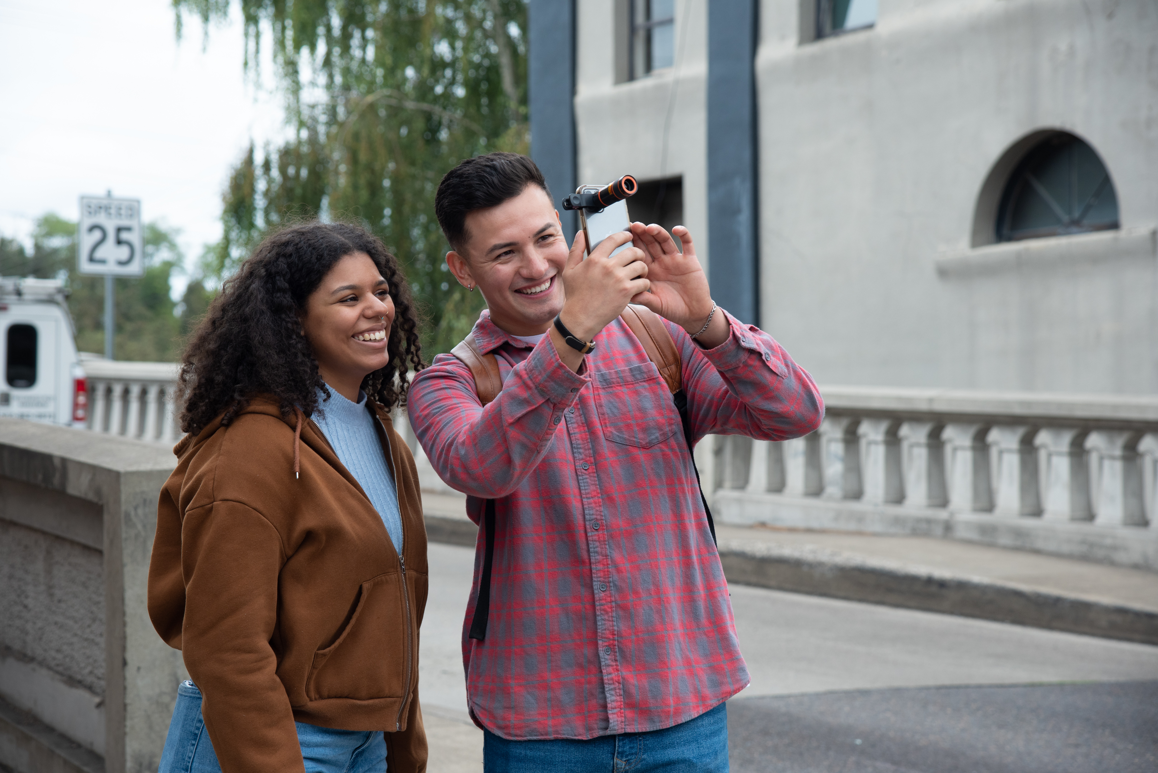 two individuals using a cell phone to take an observation of weather or wildlife in an urban environment.  